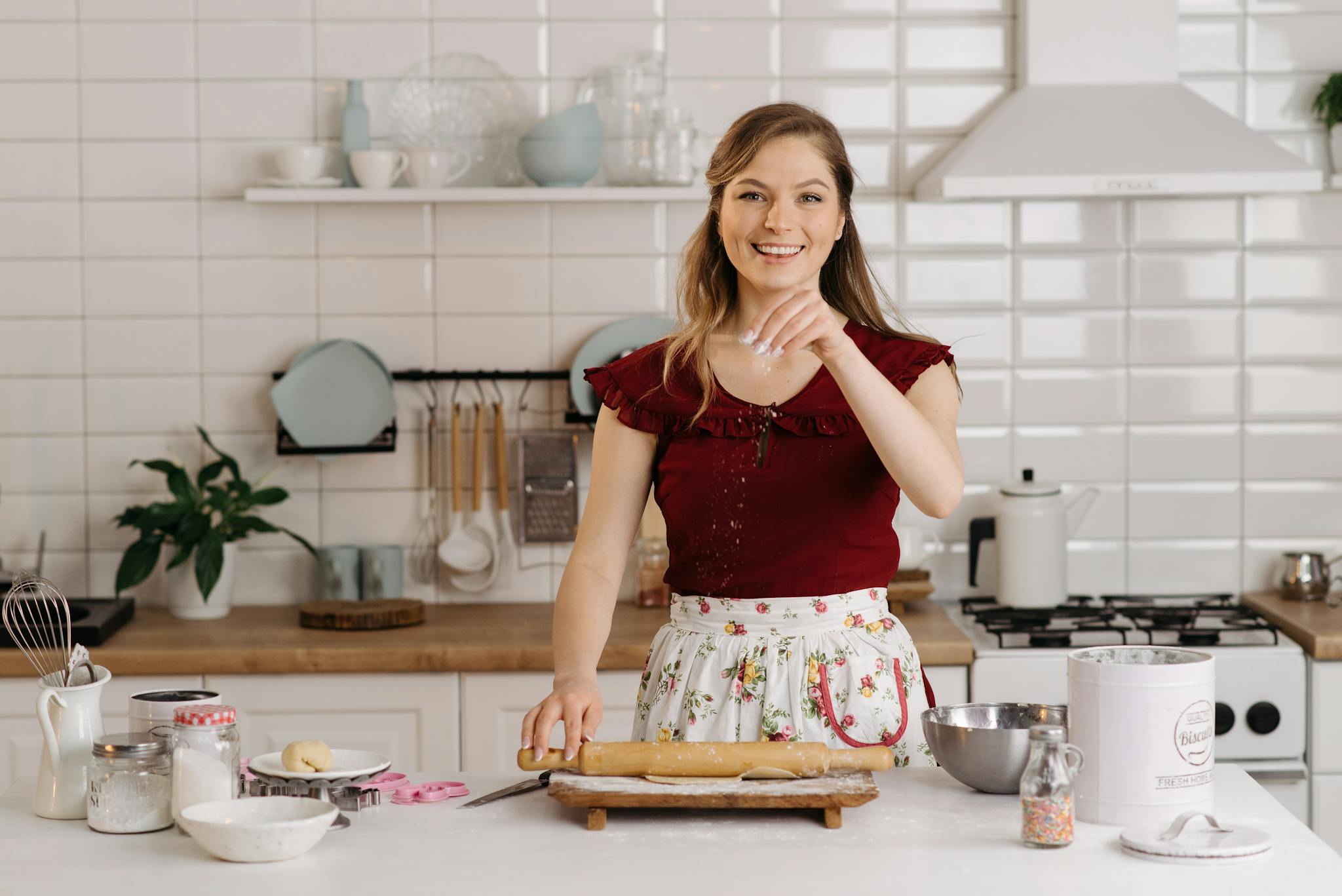 Cheerful woman preparing dough in a bright, modern kitchen setting.